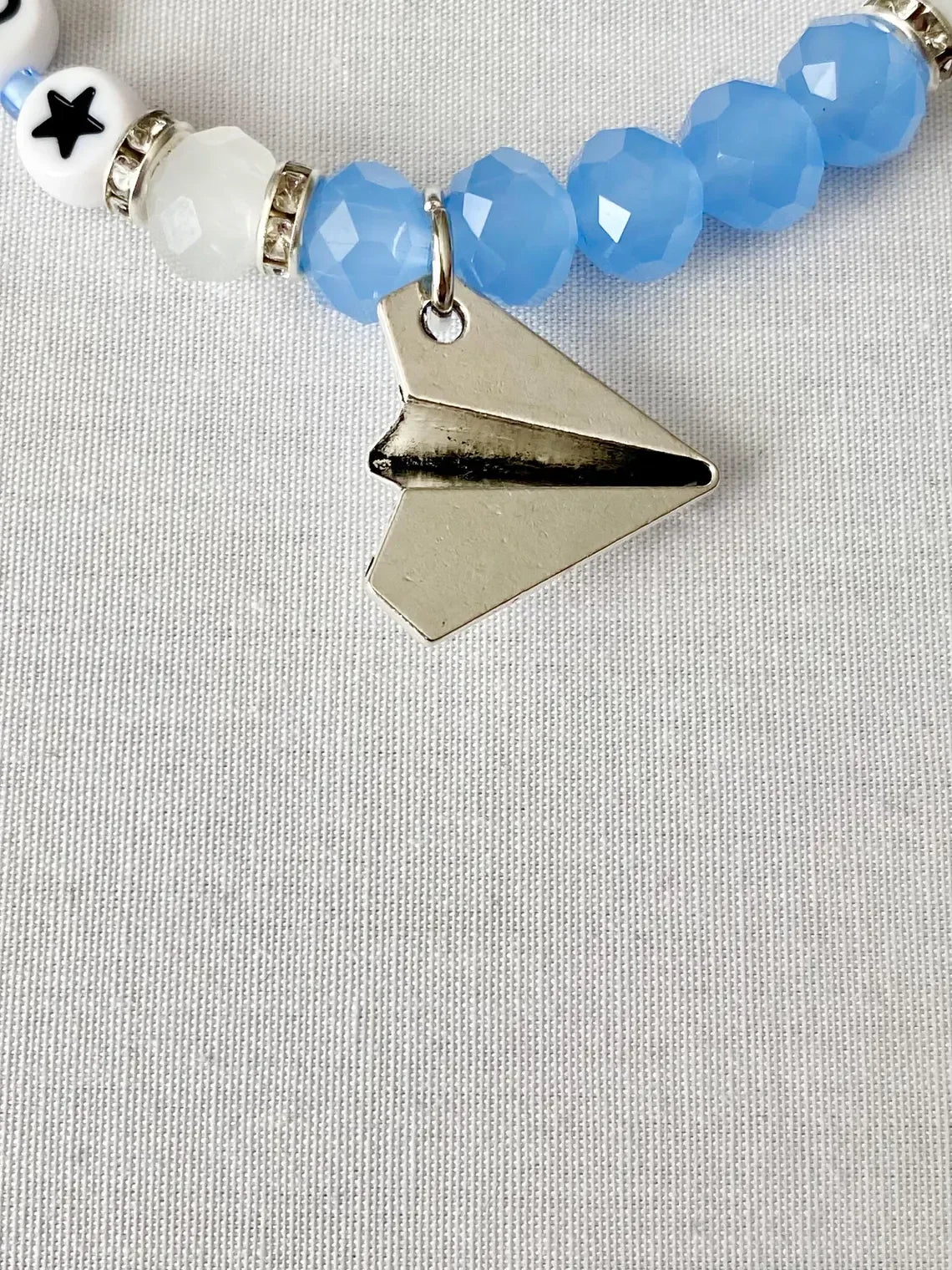 Discover the 1989 Friendship Bracelet, a Taylor Swift-inspired accessory featuring a paper airplane charm, reminiscent of the 'Out of the Woods' era. It's a perfect piece of Swiftie memorabilia for any Taylor Swift enthusiast